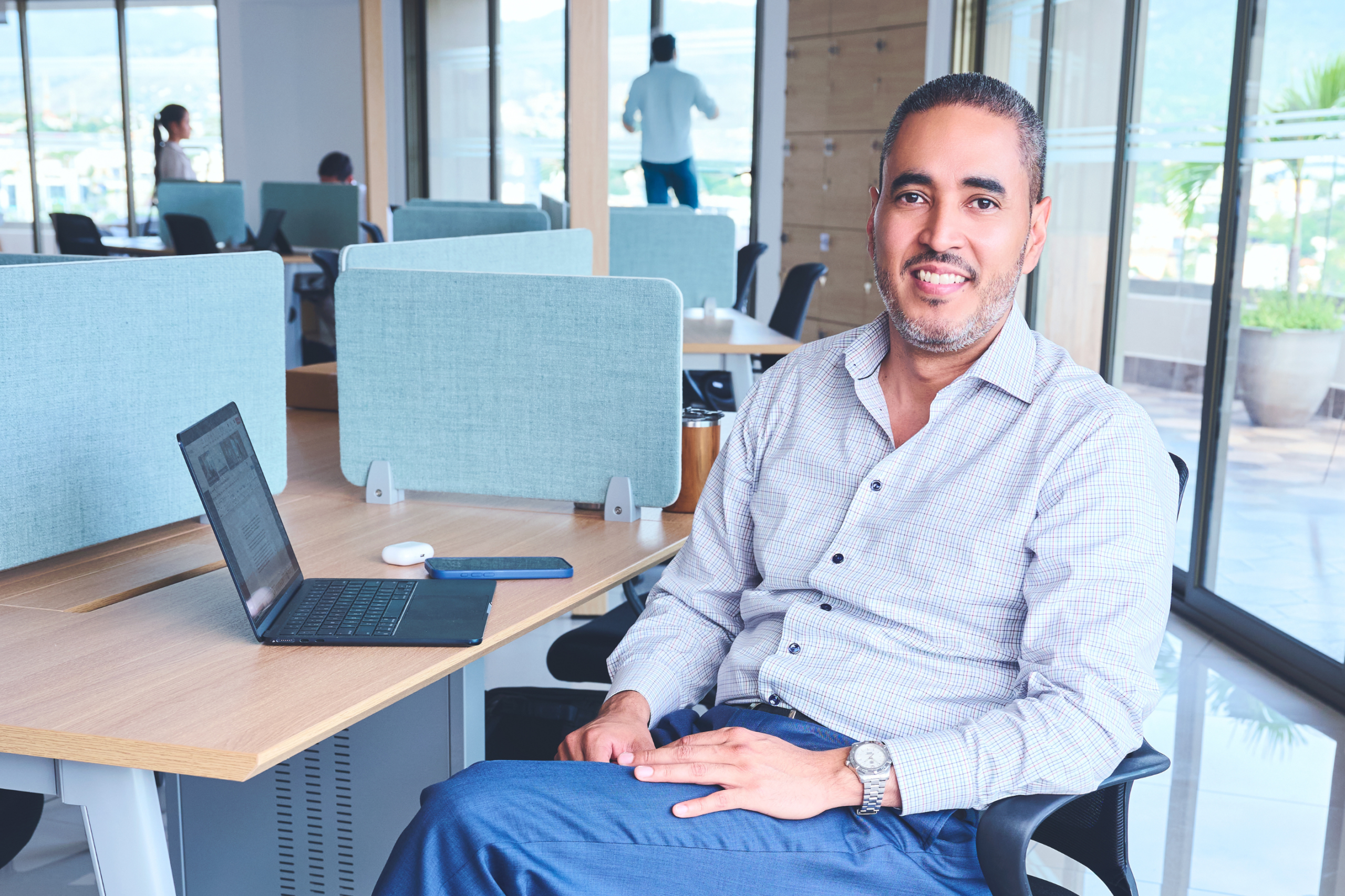 Confident businessman sitting at desk in bright, modern office setting.